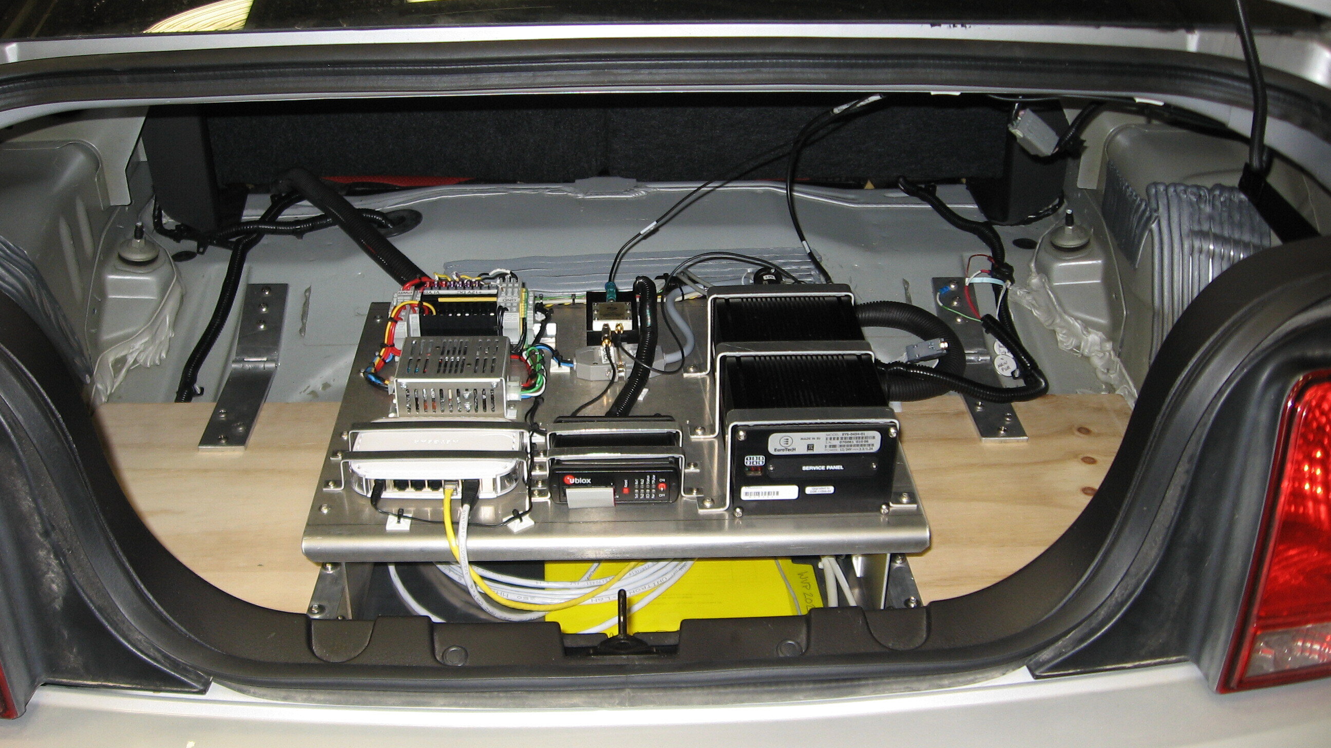 trunk of Ford Mustang with large on-board V2X signal unit inside