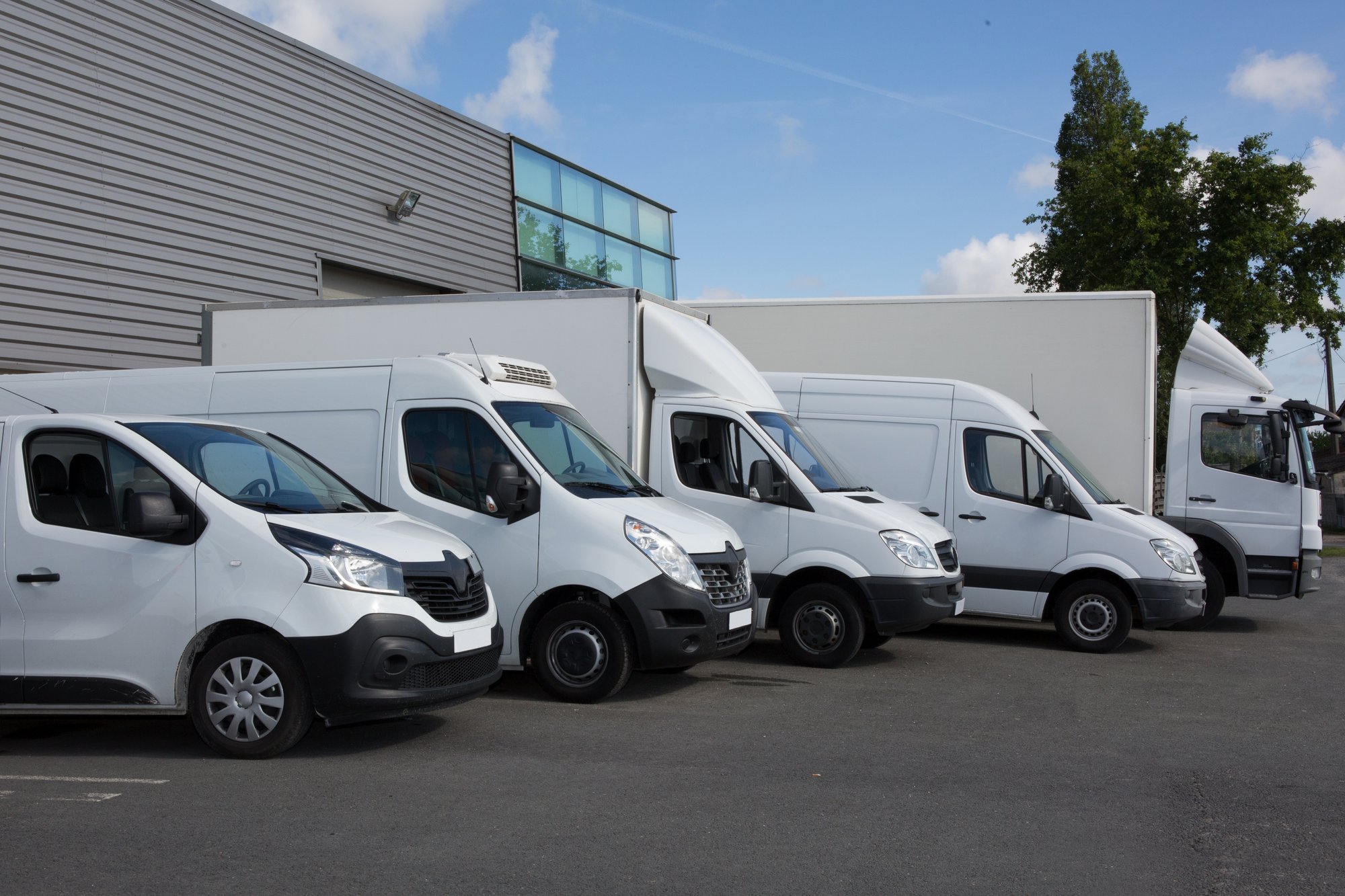 row of different sized electric delivery vehicles in parking lot