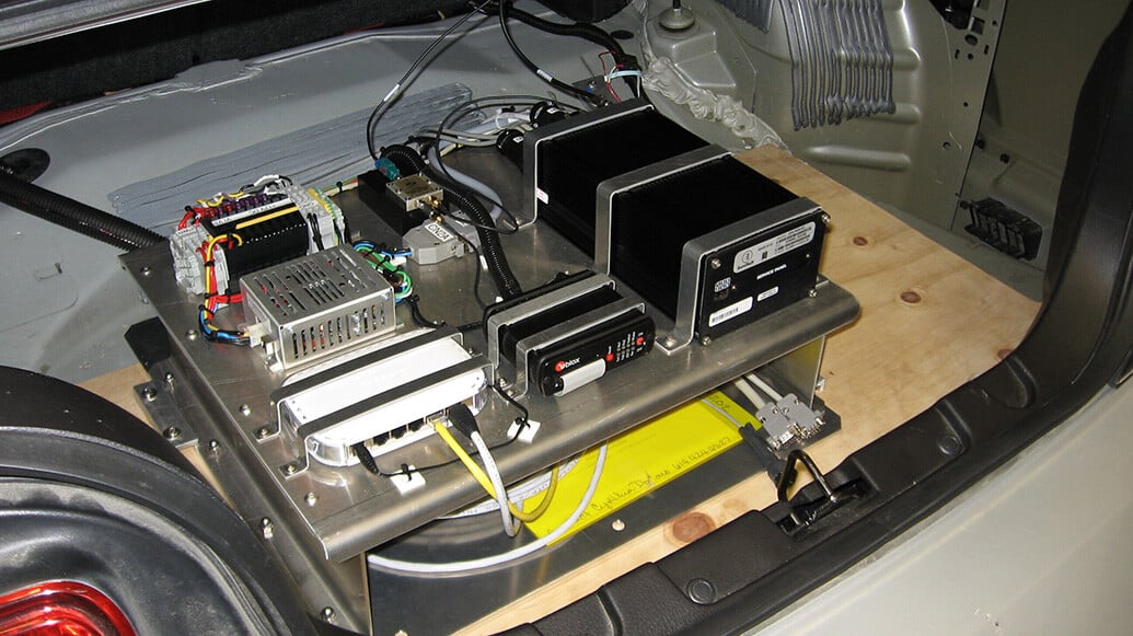 an early V2X on-board unit fills the trunk of a test vehicle